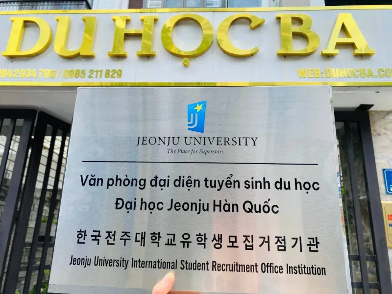 Biển Văn phòng đại diện tuyển sinh du học Đại học Jeonju Hàn Quốc trao cho Du Học BA, cầm trước biển hiệu văn phòng 82 Đặng Ma La